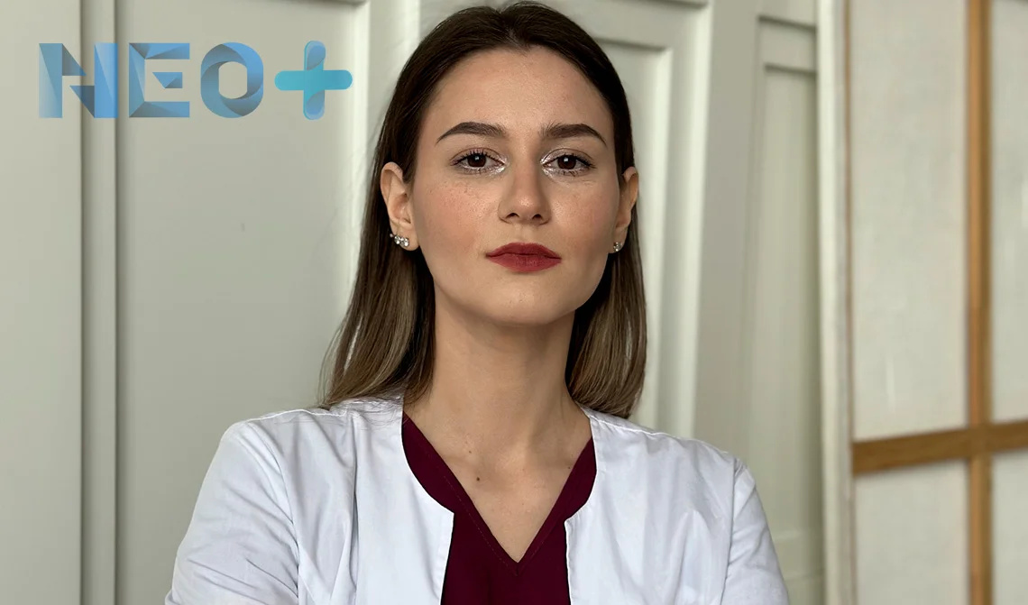 женщина врач в белом халате смотрит в камеру